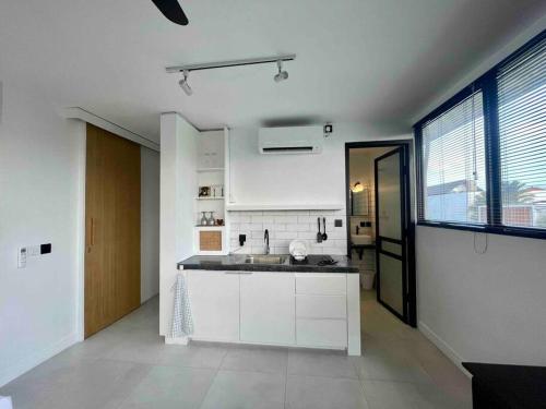 uma cozinha com armários brancos e uma grande janela em Studio Gordy em Seminyak