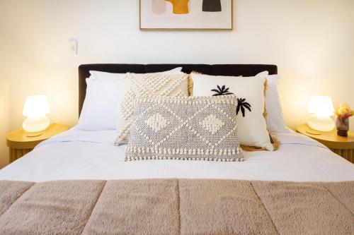 Schlafzimmer mit einem Bett mit weißer Bettwäsche und Kissen in der Unterkunft Charming Riccarton Abode 2Bed w/Garage in Christchurch
