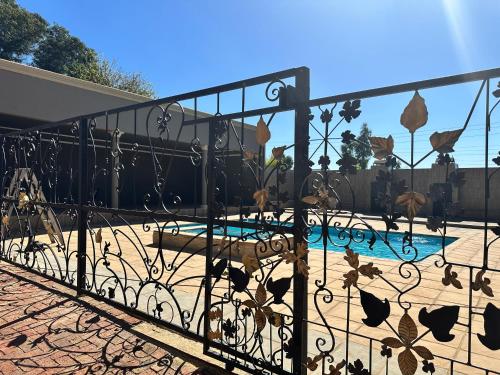 een ijzeren hek met een zwembad in een tuin bij Sekgome Resort in Johannesburg
