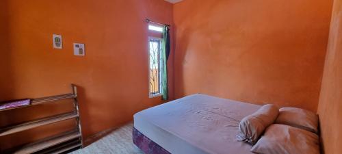an orange room with a bed and a window at Dam Ri Private 2nd Floor - Near Airport & Batukaras in Tjidjulang