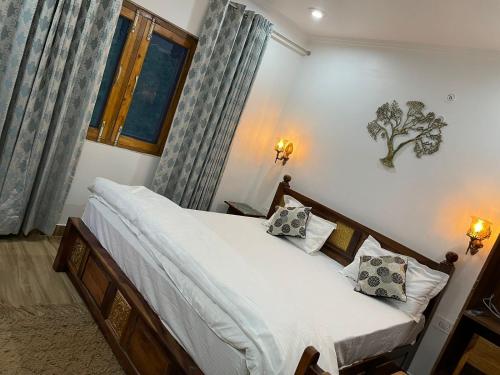 een slaapkamer met een bed met witte lakens en kussens bij Mrig Valley Resort, Homestay & Banquet in Kandikhal