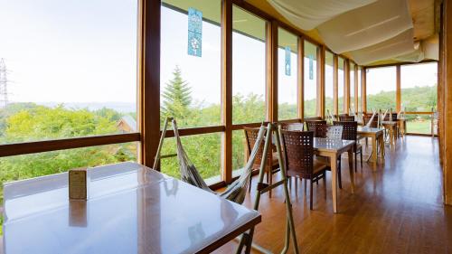 a row of tables and chairs in a room with windows at Matsue Forest Park in Matsue