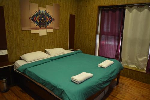 a bedroom with a bed with two towels on it at Utopia Hostels Dharamkot Mcleodganj in Dharamshala