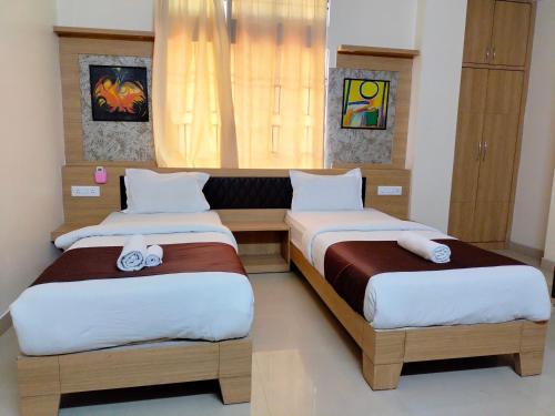 a bedroom with two beds and a window at Hotel Jaysha in Guwahati