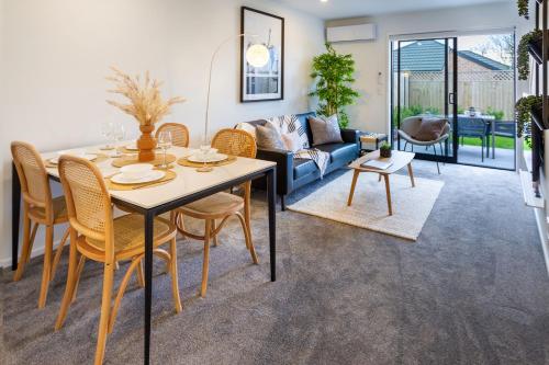 ein Wohnzimmer mit einem Tisch, Stühlen und einem Sofa in der Unterkunft Charming Riccarton Abode 2Bed w/Garage in Christchurch