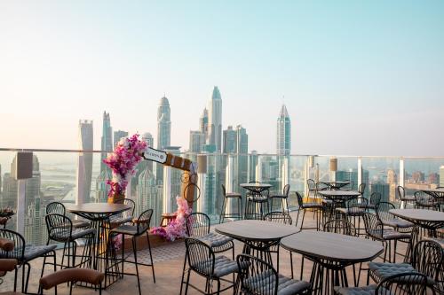 a balcony with tables and chairs and a city skyline at Taj Jumeirah Lakes Towers in Dubai