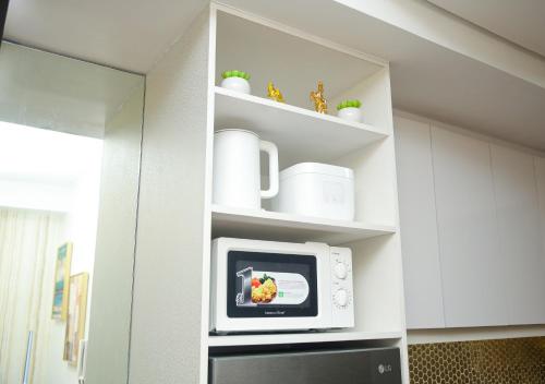 a microwave in a kitchen with white cabinets at Shore2 Luxurious & Homely Suite near MOA in Manila