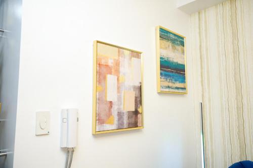 three paintings hanging on a wall in a room at Shore2 Luxurious & Homely Suite near MOA in Manila