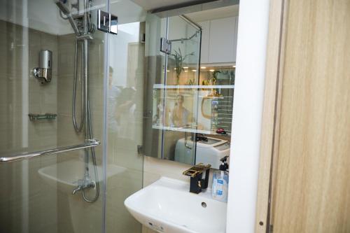 a bathroom with a sink and a shower with a mirror at Shore2 Luxurious & Homely Suite near MOA in Manila