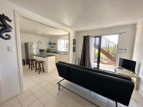 a living room with a couch and a kitchen at Bayview Beach House - Pet Friendly Holiday Home with a Pool - Holiday Yamba in Yamba