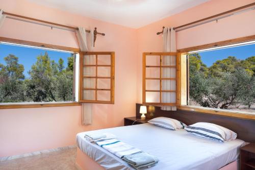 a bedroom with two windows and a bed with white sheets at Villa Sterna in Loutraki