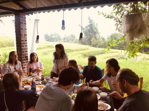 Un gruppo di persone seduti intorno a un tavolo che mangiano cibo di Cơmlam Eco House a Sa Pa