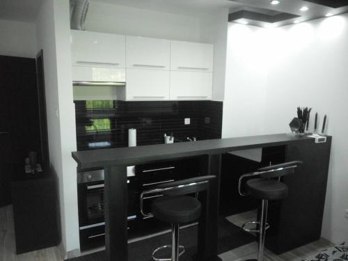 a kitchen with a black counter and stools at Fészek Apartman in Debrecen