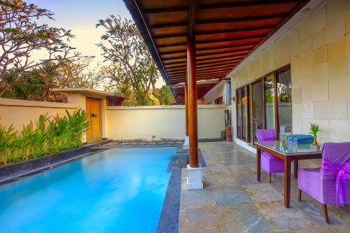 a swimming pool with a table and purple chairs at Private Pool Villas Kuta Bali in Kuta