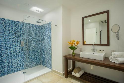 a bathroom with a sink and a shower with a mirror at The Oyster Bay Hotel Suites in Dar es Salaam