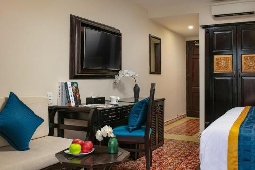 a living room with a couch and a desk with a television at La Charm Hoi An Hotel & Spa in Hoi An
