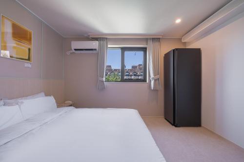 a bedroom with a bed and a black refrigerator at Workers Hotel Ansan by Aank in Ansan