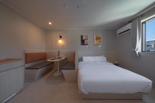 a bedroom with a white bed and a small table at Workers Hotel Ansan by Aank in Ansan