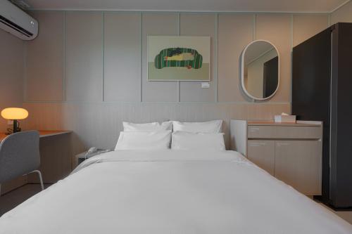 a bedroom with a large white bed and a mirror at Workers Hotel Ansan by Aank in Ansan
