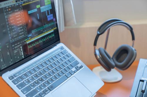 a laptop computer sitting on top of a desk with headphones at Workers Hotel Ansan by Aank in Ansan