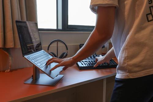 a person standing in front of a laptop computer on a desk at Workers Hotel Ansan by Aank in Ansan
