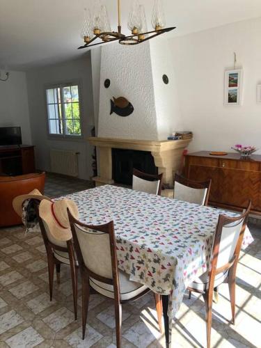 une salle à manger avec une table et des chaises et une cheminée dans l'établissement Charmante Maison proche d une calanque, à Sausset-les-Pins