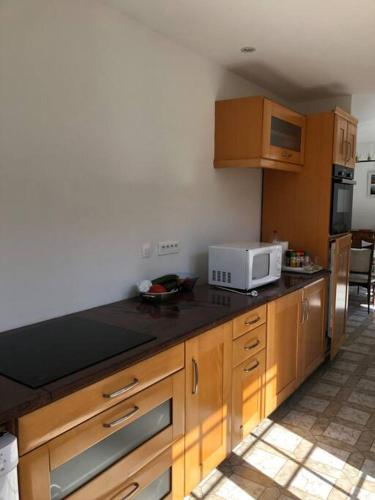 une cuisine avec des placards en bois et un four micro-ondes sur un comptoir dans l'établissement Charmante Maison proche d une calanque, à Sausset-les-Pins