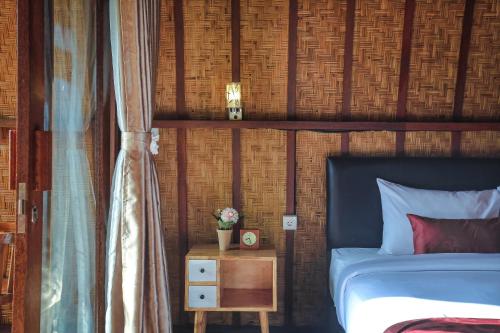 a bedroom with a bed and a table with a night stand at Navalia Villa Bedugul in Bedugul