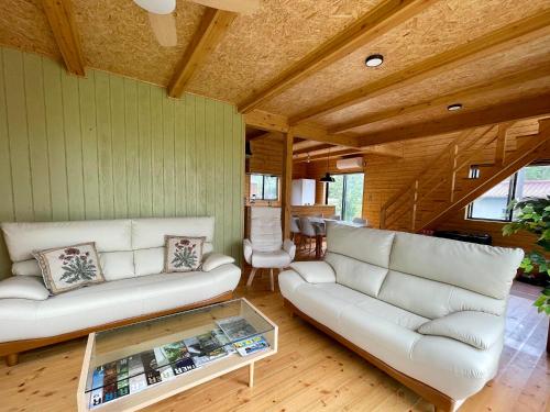 a living room with white couches and a glass table at Kujukuri SOSA -九十九里 海辺のコテージ SOSA- in Sosa