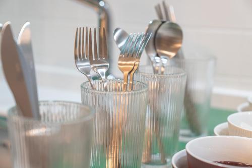a group of forks and spoons in glass cups at Workers Hotel Ansan by Aank in Ansan