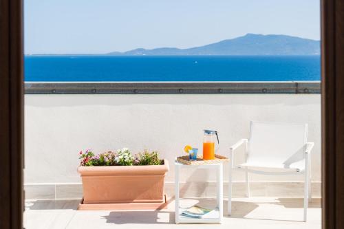 uma varanda com mesa e cadeiras e vista para o oceano em Hotel Il Telamonio em Talamone