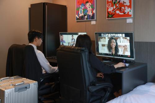 two people sitting at a desk playing a video game at Workers Hotel Ansan by Aank in Ansan
