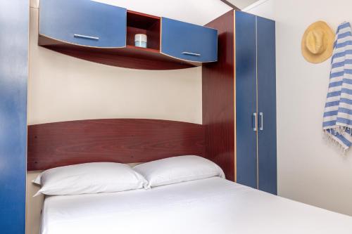 a bed with a wooden headboard and a blue cabinet at Gitavillage Le Marze in Marina di Grosseto