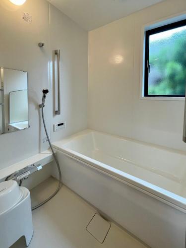 a white bathroom with a bath tub and a sink at Kujukuri SOSA -九十九里 海辺のコテージ SOSA- in Sosa