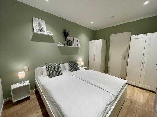 ein Schlafzimmer mit einem großen weißen Bett und grünen Wänden in der Unterkunft Condo Apartments Hamburg in Hamburg