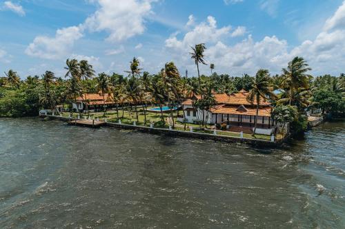 une maison au bord d'une rivière avec des palmiers dans l'établissement Cocobay Resort Kumarakom, à Kumarakom