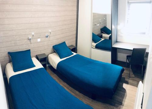 a bedroom with two beds with blue sheets and a mirror at Paradis De Bellevue in Puymiclan