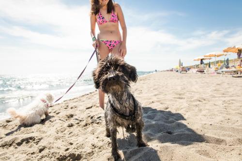 Una ragazza in bikini che porta a spasso il cane sulla spiaggia di Gitavillage Le Marze a Marina di Grosseto