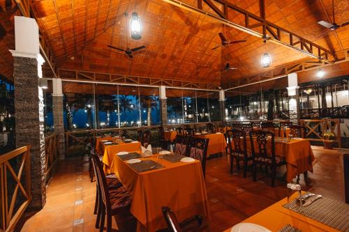 a restaurant with tables and chairs in a room at Cocobay Resort Kumarakom in Kumarakom