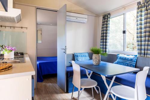 a kitchen and dining room with a blue table and chairs at Gitavillage Le Marze in Marina di Grosseto