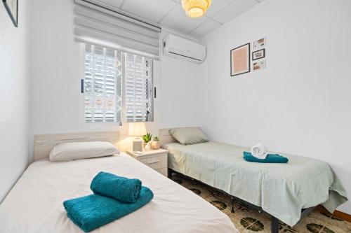 two beds in a white room with blue towels on them at Casa Plugge in Torrevieja