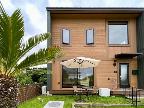 a house with a table and an umbrella in front of it at Kujukuri SOSA -九十九里 海辺のコテージ SOSA- in Sosa
