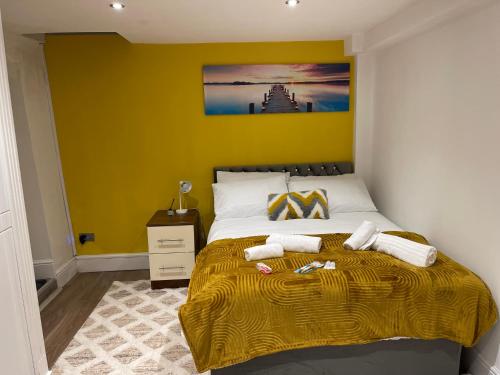 a bedroom with a bed with a yellow wall at Central Cheltenham Apartment in Cheltenham