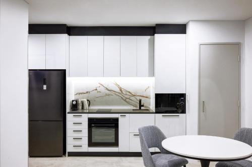 a kitchen with a table and a black refrigerator at Meriton Suites Liverpool in Liverpool