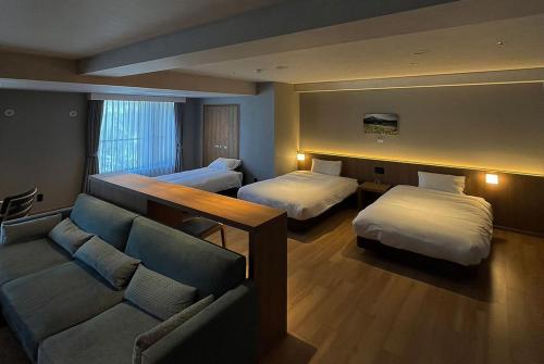 a hotel room with two beds and a couch at Higashikawa Asahidake Onsen Hotel Bear Monte in Higashikawa