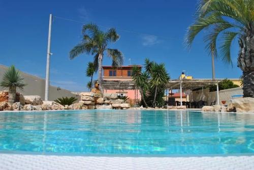 a large swimming pool with palm trees and a house at Il Germoglio in Bisceglie