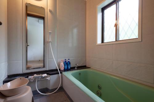 AnazawaにあるS-villa Nasu 6thのバスルーム(緑のバスタブ、トイレ付)、窓が備わります。