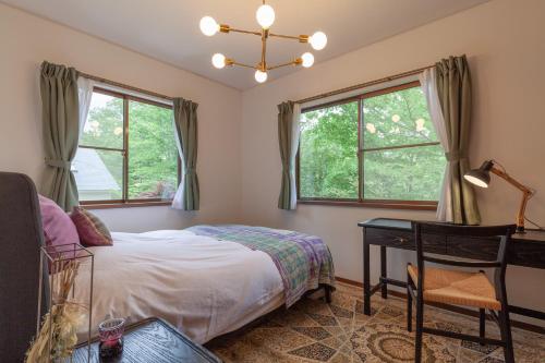 a bedroom with a bed and a desk and windows at S-villa Nasu 6th in Anazawa