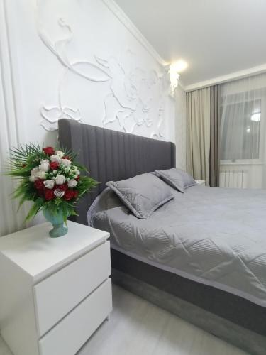 een slaapkamer met een bed en een vaas met bloemen bij Трёхкомнатная квартира ВИП in Köksetaw