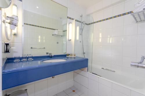 W łazience znajduje się niebieska umywalka i lustro. w obiekcie Hotel Etats Unis Opera w Paryżu